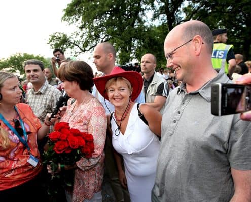 Mona Sahlin intervjuas, Tomas Östros står bredvid. En kvinna sticker in huvudet emellan dem för att kunna fotas med dem
