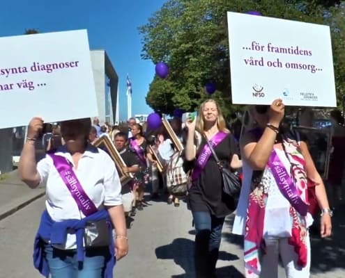 Parad där människor håller skyltar med texterna "Sällsynta diagnoser banar väg..." och "....för framtidens vård och omsorg"